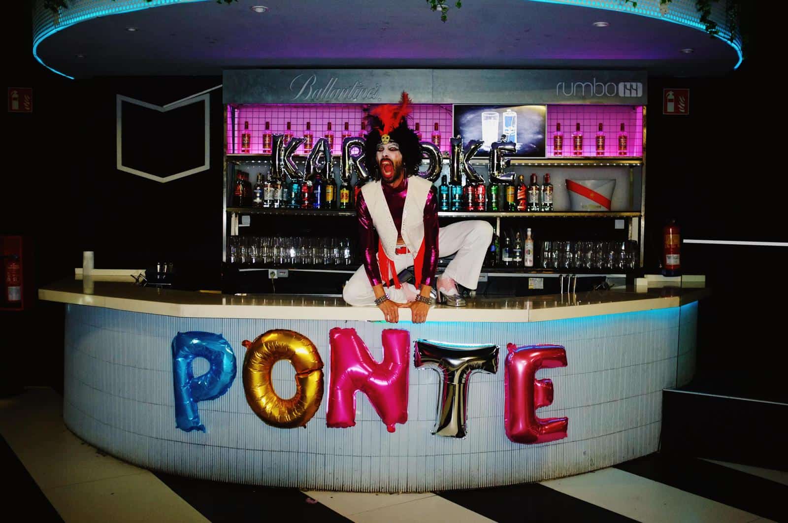Vedra Ponte en un escenario de karaoke con decoración colorida y ambiente festivo.